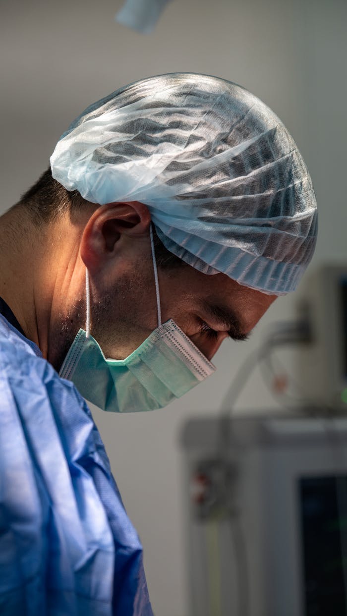 Surgeon in protective gear intensely focused during a medical procedure, highlighting healthcare professionalism.