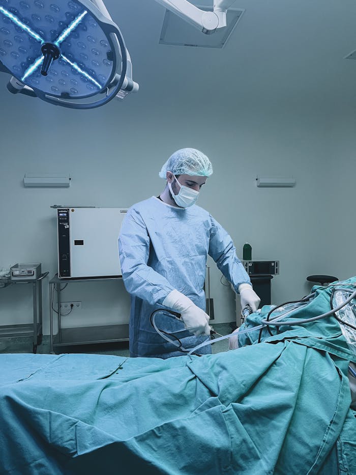 A surgeon in a blue gown performing an endoscopic procedure in an equipped operating room.