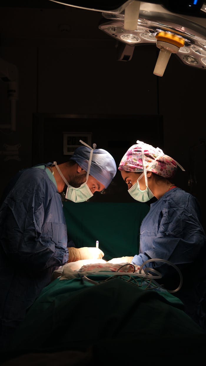Focused surgeons performing surgery under dramatic lighting in a hospital operating room.